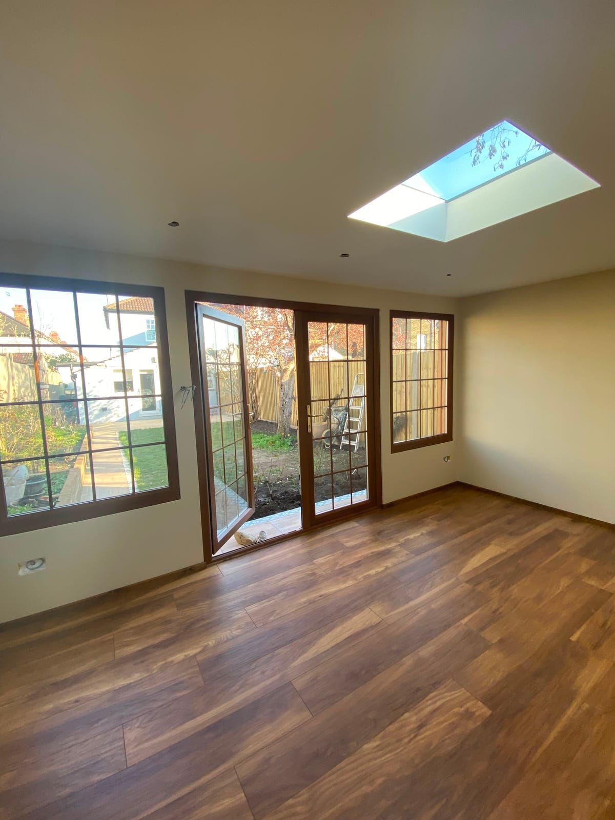 Empty garden room interior with a roof lantern overhead and hardwood French doors open onto the garden