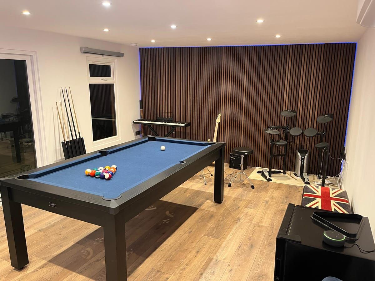 Games room interior with a pool table, backlit acoustic slat wall, electric drum kit and keyboard