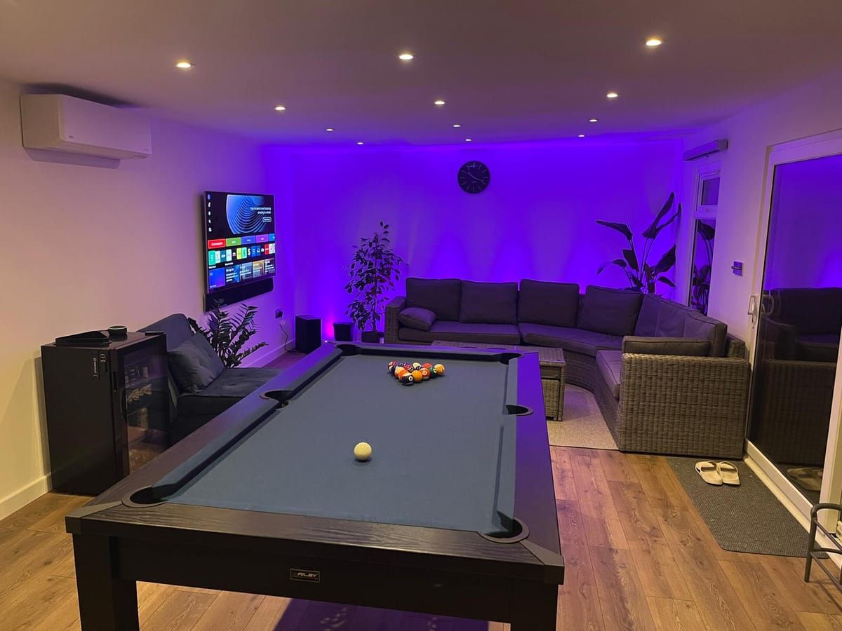 Games room with pool table, corner sofa, wall-mounted television and colour-changing LED lighting
